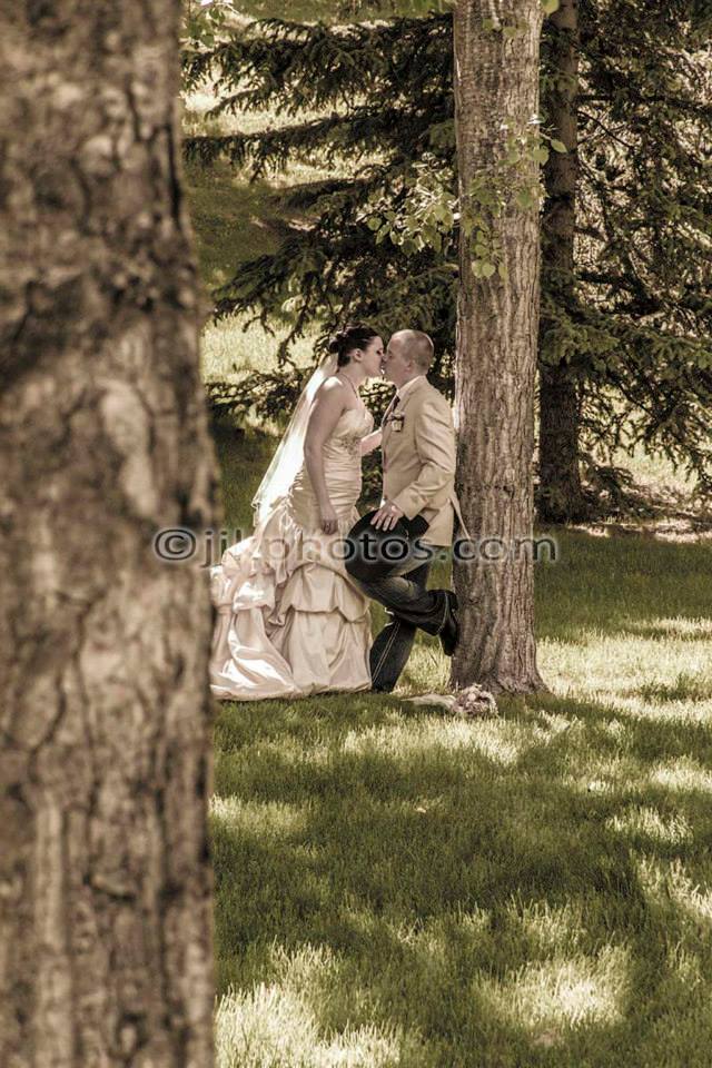 Wedding couple embracing beneath a tree